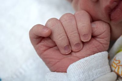 Cropped hand of newborn baby relaxing on bed