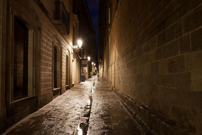 Empty alley amidst buildings at night