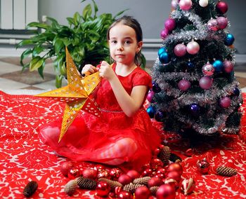 A little girl in a festive red dress holds a paper gold star decorative decor. new year 