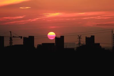 Silhouette buildings against sky during sunset in city