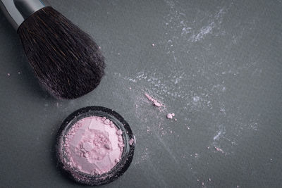 High angle view of make-up brush and eyeshadow on table