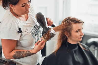 Hairdresser drying woman hair in salon