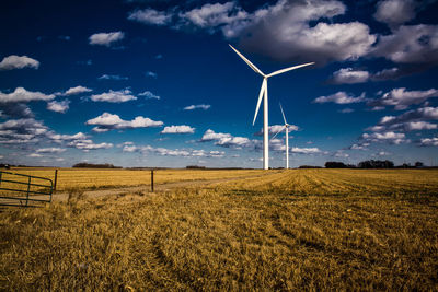 Wind turbines on field against blue sky