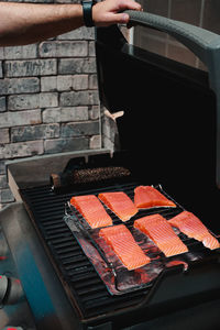 Cropped hand of person preparing food on barbecue grill