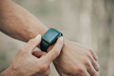 Cropped hand of men wearing smart watch outdoors