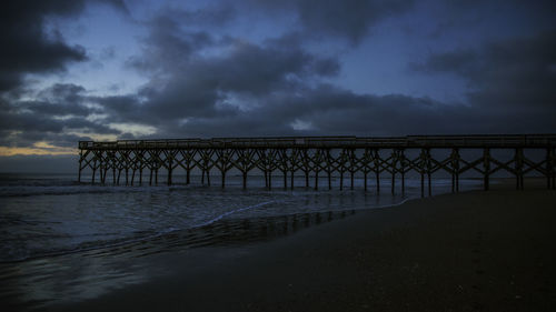 Bridge over sea against sky during sunset