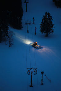 High angle view of snowcat on snow covered field at night