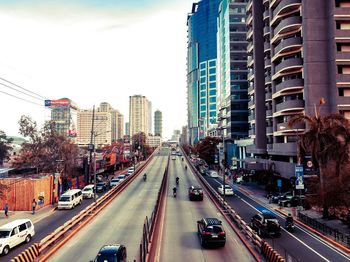 Traffic on city street amidst buildings against sky