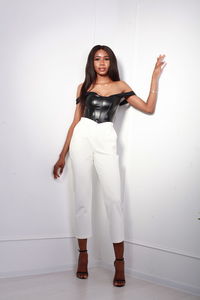 Portrait of young woman standing against white background