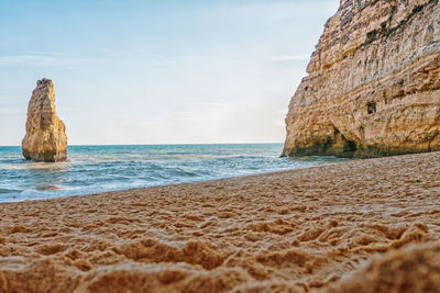 Rock formation on beach against sky