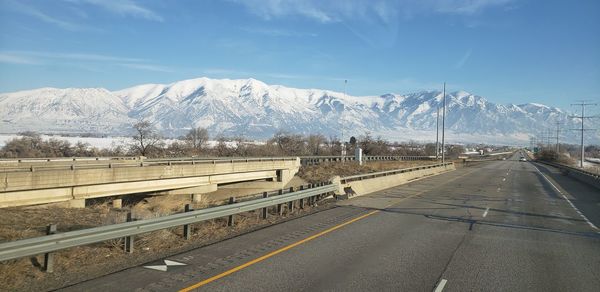 Road leading towards snowcapped mountains against sky