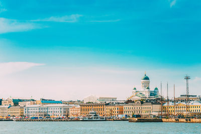 View of buildings by river against sky in city