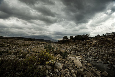 Rocks on field against cloudy sky