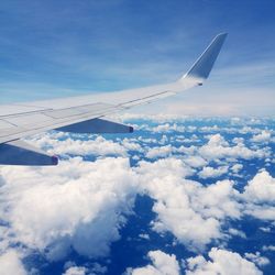 Airplane wing over clouds against blue sky