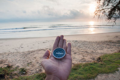 Hand with compass on beach