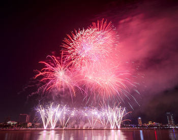 Low angle view of firework display over river at night