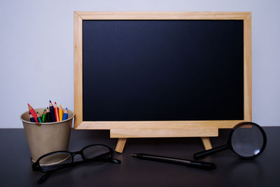 Close-up of blank blackboard with school supplies on table