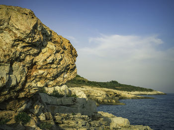 Rock formations by sea against sky