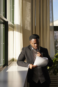 Side view of businessman using mobile phone while standing in office