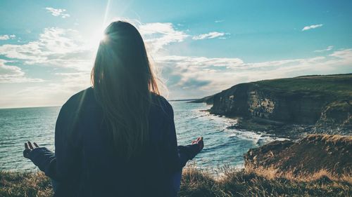 Rear view of woman looking at sea from cliff