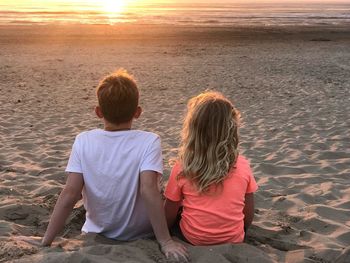 Rear view of friends sitting at beach