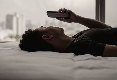 Asian man feels sad on bed looking and focus on smartphone. mental health concept.