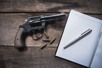 High angle view of pen on book by gun over table