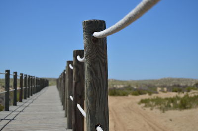 Wooden posts on land against clear sky