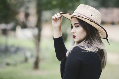 Portrait of young woman wearing hat standing outdoors