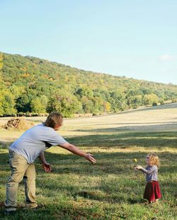 Rear view of a couple on grassland against clear sky