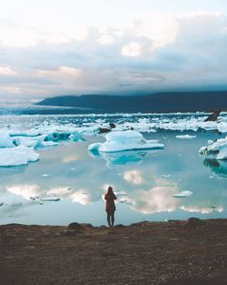 Rear view of woman standing against ice bergs