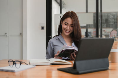 Young woman using phone while sitting on table