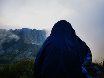 Rear view of woman standing on mountain against sky