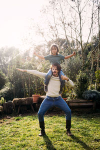 Father playing with his son, carrying him piggyback in a garden