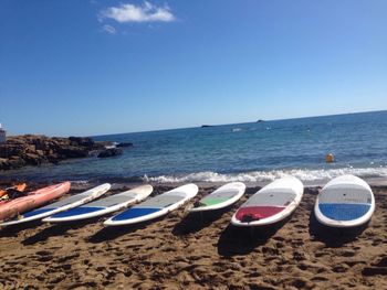 Boats on sandy beach against blue sky