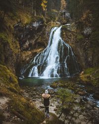 Man standing by waterfall