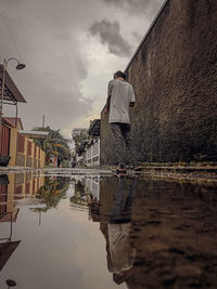 Rear view of man standing by lake against sky