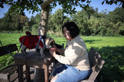 Mid adult woman feeding dog while sitting in park