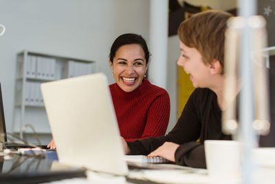 Cheerful multi-ethnic female professionals working at desk in creative office