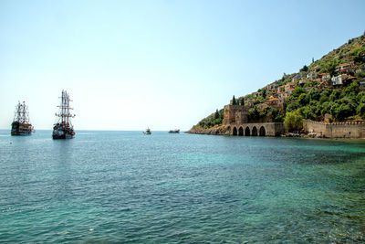 Sailboats in sea against clear sky