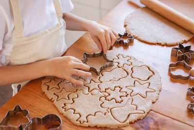 Children with their mother cut out christmas gingerbread cookies. family holiday cooking.