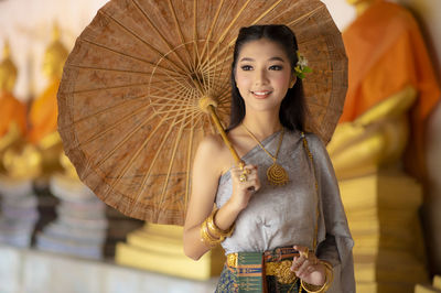 Young woman in traditional clothing with umbrella standing at temple