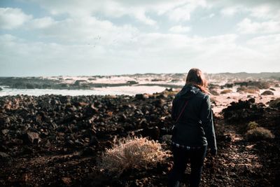 Rear view of woman standing by sea against sky