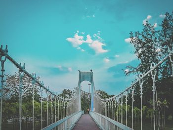 Footbridge against cloudy sky