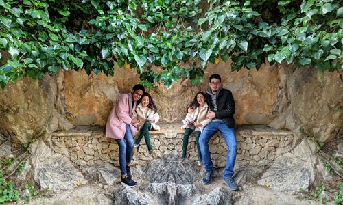 Rear view of people sitting on rock