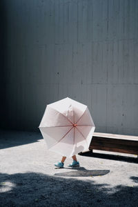 Low section of woman holding umbrella on wall