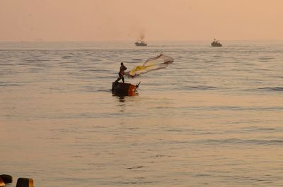 People on boat in sea against sky during sunset