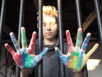 Low angle view of boy showing painted hands through window