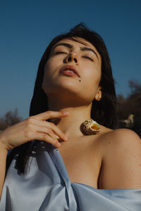 Portrait of woman looking away against blue sky