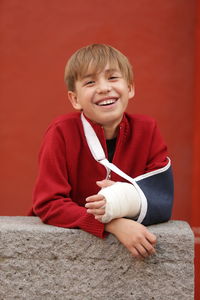 Portrait of smiling boy with orthopedic cast standing outdoors